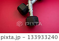 Close-up of black dumbbells resting on a striking red surface, highlighting their sleek design and material quality, with a smooth zoom in capturing intricate details 133933240