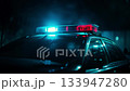 Powerful police car emergency lights illuminating dark urban street, signaling urgent law enforcement presence and heightened nighttime security atmosphere 133947280