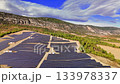 Aerial footage of a massive solar farm with rows of photovoltaic panels generating clean, renewable energy in a sunny, rural landscape 133978337