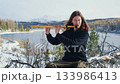 Long-haired musician playing a wooden flute in a snowy mountain landscape 133986413