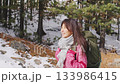 Happy asian woman hiker walking in a snowy winter forest 133986415