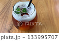 cold iced tea in a rounded glass, topped with foam and fresh mint, with a black straw. Inviting and casual, perfect for summer cafe or lifestyle imagery, Refreshing Iced Tea Glass With Mint Garnish An 133995707