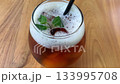 cold iced tea in a rounded glass, topped with foam and fresh mint, with a black straw. Inviting and casual, perfect for summer cafe or lifestyle imagery, Refreshing Iced Tea Glass With Mint Garnish An 133995708