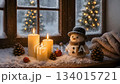 冬の窓辺に灯るキャンドルと雪だるまの温かいクリスマスシーン 134015721