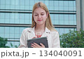 Young caucasian businesswoman writing on digital tablet in city. 134040091