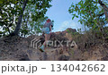 Full Body Shot of a determined woman with colored hair navigating a rough, outdoor climbing challenge 134042662