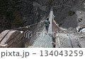 High Altitude Trekking Solo Traveler crossing a long suspension bridge. Nepal, Annapurna circuit trek. 134043259