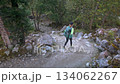 Following a trekker as she carefully steps over boulders on a rugged and remote natural route. 134062267