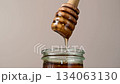 Jar of honey with wooden dipper, sweet liquid, neutral background 134063130