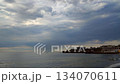 Rainy weather at sea near urban coast. Dark cloudy rainy clouds in sky, blue calm water surface of sea waves. Rain falling in sea. Seascape. Sea landscape. Seagulls swimming in the water 134070611