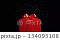 Red gift box with a bow and golden confetti on festive glittering bokeh background 134093108