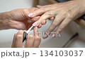 Close up Step by Step French Manicure on Mature Hands in Salon. Application of the white tip 134103037