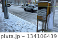 Countermeasures against frozen roads in Sapporo in winter. A car driving on a snowy road with a box of anti-slip sand. 134106439