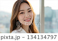 A beautiful Korean woman smiling, with long hair, in an office background with a cityscape_5 134134797