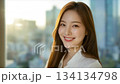 A beautiful Korean woman smiling, with long hair, in an office background with a cityscape_4 134134798