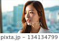 A beautiful Korean woman smiling, with long hair, in an office background with a cityscape_3 134134799