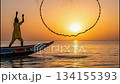 A person in Senegal animates a circular fishing net, allowing it to open fully as it descends into the water. The sun sets, creating a beautiful backdrop for fishing. 134155393