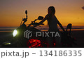Silhouette of woman with motorcycle posing on the beach at sunset 134186335