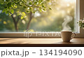 A cafe scene in early summer with steaming coffee on a windowsill surrounded by fresh greenery (loop video) 134194090