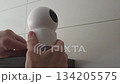 Installing and adjusting modern security camera on wall shelf for enhanced home safety. Security camera - unplugs and blue indicator lights go out 134205575