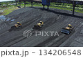 Aerial view of bulldozers directing coal to conveyor belts at a thermal power plant during daylight operations 134206548