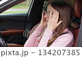 Woman in car sitting in driver seat with hands on temples, eyes closed, suffering from headache, stress, tension or migraine, feeling overwhelmed. 134207385