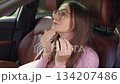 Woman in car adjusting hair and glasses, touching her face while looking in the mirror, preparing for work in the morning. Get Ready Concept. 134207486