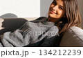 セーター姿でソファーに寝転ぶ綺麗な女性 134212239