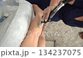 Vertical close up video of professional cosmetologist doing laser hair removal of legs to young woman in beauty salon 134237075