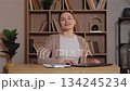 Caucasian woman closing laptop after finishing work at wooden desk. Female ending remote job tasks feeling content sitting in quiet home office with bookshelves and indoor plants in background. 134245234