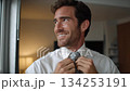 close up of happy man in white shirt putting tie on 134253191