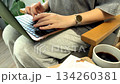 A woman works with a laptop on her lap, typing steadily as she concentrates in a peaceful and comfortable environment. 134260381