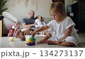 Little girl plays with a toy truck on the floor while mother and father relax 134273137