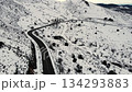 Aerial drone video following a winding mountain road through a snowy winter landscape. Curved 134293883