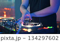 A close-up shot captures the hands of a DJ actively mixing music on a professional turntable 134297602