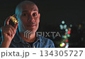 Confident bald man showing a small gold bar at night 134305727