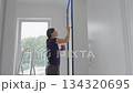 Woman painting interior wall with brush and masking tape 134320695