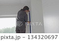 Woman applying masking tape on wall corner before painting 134320697