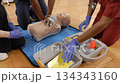 Medical students practicing CPR and defibrillator use on a mannequin 134343160