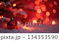 Red Christmas ornament resting on a snowy pine branch. Festive holiday background with glowing bokeh lights creating a magical atmosphere 134353590