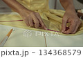Woman seamstress sleeve length measurement on a shirt using a tape measure by a tailor. 134368579