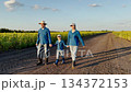 Country family enjoying outdoor time, teaching responsibility to children, sunflower farm beside the path, nostalgic farm life, generations of agricultural knowledge, walking towards a bright future 134372153