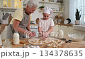 Happy family in kitchen. Grandmother granddaughter child cutting cookies of dough on kitchen table together. Grandma teaching kid girl cook bake cookies. Household teamwork helping family generations 134378635