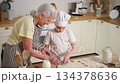 Happy family in kitchen. Grandmother granddaughter child cutting cookies of dough on kitchen table together. Grandma teaching kid girl cook bake cookies. Household teamwork helping family generations 134378636