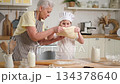 Happy family in kitchen. Grandmother and granddaughter child cook in kitchen together. Grandma teaching kid girl roll out dough bake cookies. Household teamwork helping family generations concept 134378640