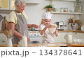 Happy family in kitchen. Grandmother and granddaughter child cook in kitchen together. Grandma teaching kid girl knead dough bake cookies. Household teamwork helping family generations concept 134378641