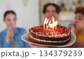 Make a wish. Burning candles on birthday cake ready for blowing out. Happy Birthday party. Friends wishes man happy birthday. People celebrating birthday party. Plate with cake in hands 134379239