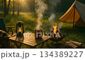 キャンプの朝、マグカップから立ち上る湯気と焚き火 134389227