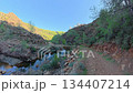Hiking trail alongside stream in canyon leading to Toparlar Waterfall in Mugla, Turkey with rocky cliffs and lush vegetation 134407214