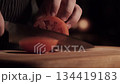 A chef with a very sharp knife cuts off a piece of tomato for a burger in one move. Close-up high quality 4k footage 134419183
